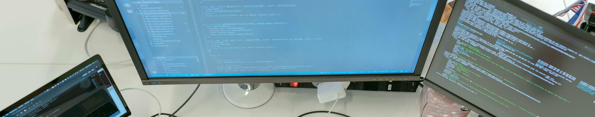Développeur web travaillant simultanément sur plusieurs écrans.